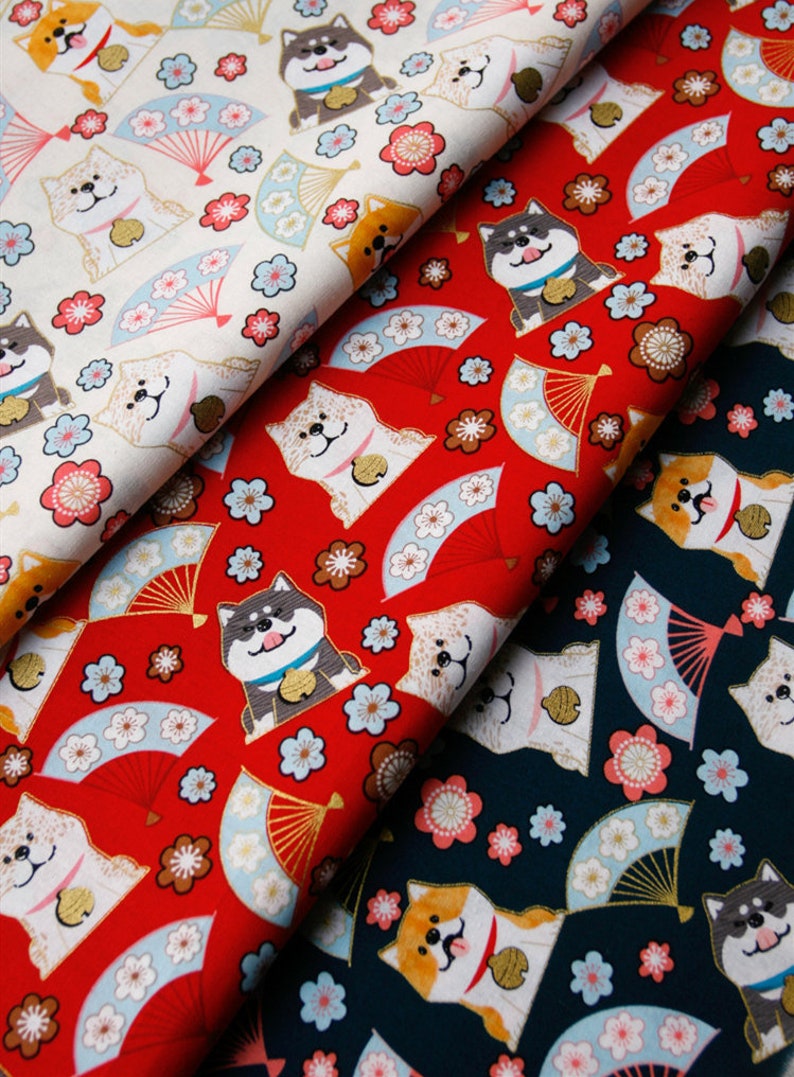 Puede incluir: Tela con un patr&oacute;n repetido de perros Shiba Inu, abanicos y flores en rojo, blanco y azul marino. Los perros tienen diferentes colores y llevan collares. Los abanicos son de color azul claro y dorado, y las flores son rosas y blancas.