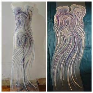 May include: A sheer, flowing garment with a swirling design of white, purple, and blue embellishments. The intricate pattern resembles flowing water or a celestial design. The garment is displayed on a mannequin and also laid flat.