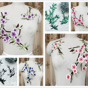 Könnte beinhalten: Sortiment an gestickten Blumenapplikationen in verschiedenen Farben, darunter Rosa, Lila, Blau und Grün. Die Applikationen zeigen zarte Blumendesigns mit filigranen Details.