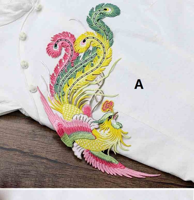 Op de afbeelding: Een kleurrijk geborduurd strijk-op-patch met een feniks met groene, gele, roze en rode accenten. De patch is in de afbeelding met "A" gemarkeerd.