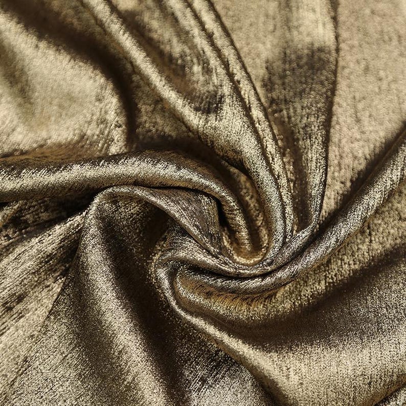 Pode incluir: Close-up de um tecido met&aacute;lico dourado com um brilho sutil e uma superf&iacute;cie texturizada.