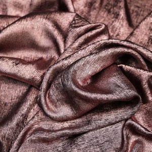 Pode incluir: Close-up de um tecido macio, rosa dourado com um brilho sutil. O tecido &eacute; drapeado e dobrado, criando uma textura luxuosa e elegante.