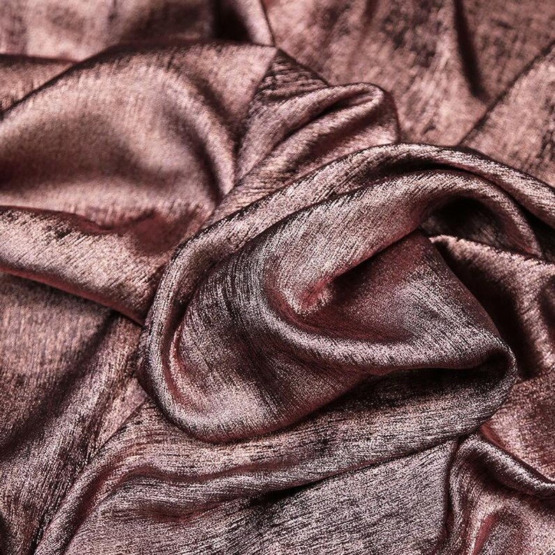 Pode incluir: Close-up de um tecido macio, rosa dourado com um brilho sutil. O tecido &eacute; drapeado e dobrado, criando uma textura luxuosa e elegante.