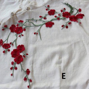 May include: White linen shirt with red embroidered flowers. The flowers are arranged in a branch-like pattern.