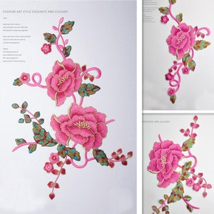 Könnte beinhalten: Rosa bestickte Blumenapplikation mit goldenen Akzenten. Die Applikation zeigt eine große rosa Blume mit kleineren rosa Blumen und grünen Blättern.