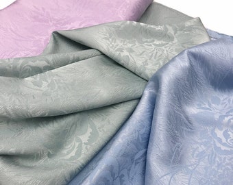 May include: Three pieces of fabric in different shades of blue and pink with a floral pattern. The fabric has a subtle sheen and a textured surface.