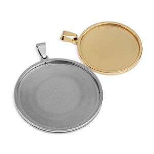 May include: Two round pendant blanks, one silver-toned and one gold-toned, are displayed against a white background. Each pendant has a circular bezel and a loop for a chain. The gold pendant is shiny, while the silver one has a matte finish.