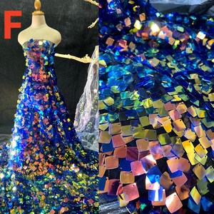 May include: A strapless gown made of blue fabric covered in iridescent square sequins. The sequins reflect colors like gold, pink, and green. The dress is displayed on a mannequin. The letter "F" is in the upper left corner.