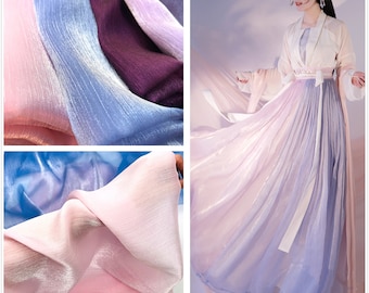 May include: A sheer fabric in shades of pink, blue, and purple with a subtle shimmer. The fabric is draped and folded to show its texture and drape.