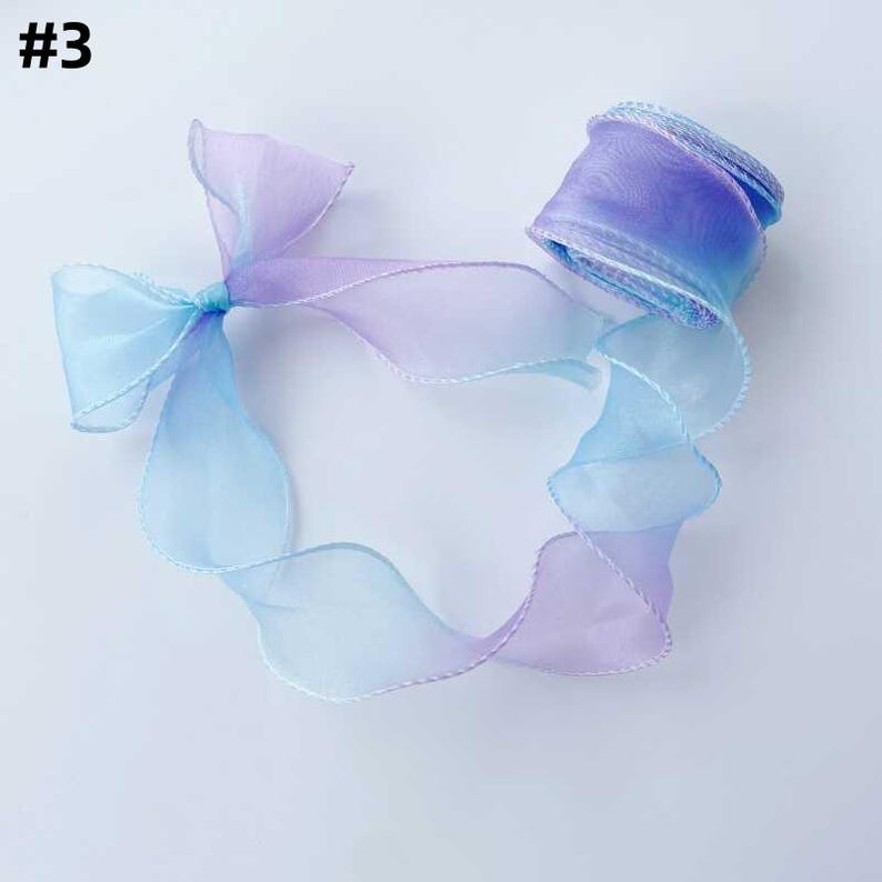 May include: A roll of ombre ribbon in shades of blue and purple, with a matching bow. The sheer ribbon has a delicate, wavy edge. The number "#3" is in the top left corner.