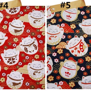 Puede incluir: Tela con un patr&oacute;n repetido de gatos de la suerte Maneki-Neko blancos con las patas levantadas, sobre fondos rojos y azul marino. Los gatos tienen detalles dorados, marrones y rojos, con motivos florales y de olas.