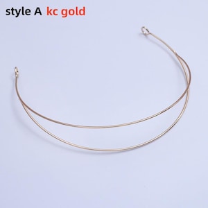 May include: A gold-colored metal headband with two parallel curved bands. The text "style A kc gold" is visible in the upper left corner. The headband has small loops at each end.
