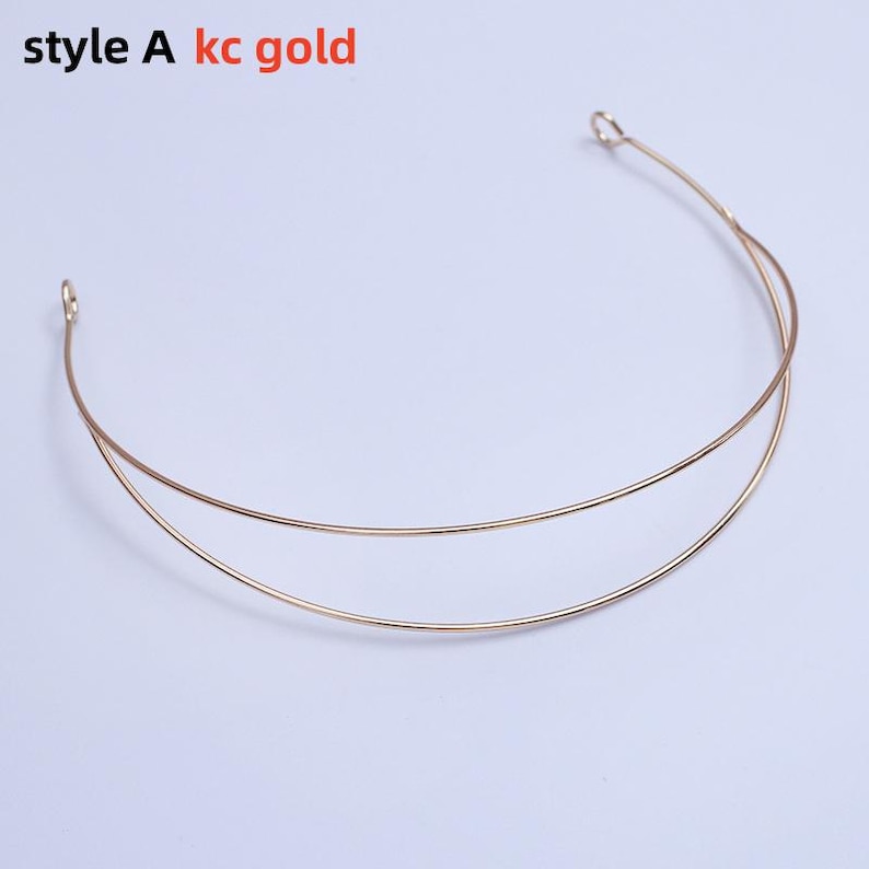 May include: A gold-colored metal headband with two parallel curved bands. The text "style A kc gold" is visible in the upper left corner. The headband has small loops at each end.