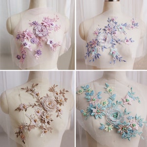 Könnte beinhalten: Vier verschiedene Spitzenapplikationen mit Blumenmustern und Perlenbesatz. Die Applikationen sind in den Farben Rosa, Blau und Beige gehalten.