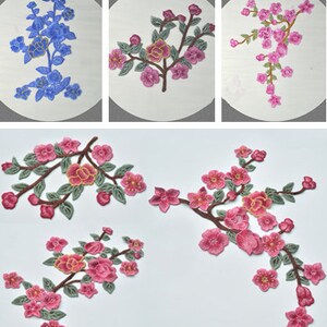 Könnte beinhalten: Fünf rosa und grüne gestickte Blumenapplikationen mit zarten Zweigen und Blättern. Die Applikationen eignen sich perfekt, um Kleidung, Taschen oder Heimtextilien einen Hauch von Eleganz zu verleihen.