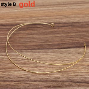 May include: A gold-colored necklace with a delicate, two-strand design. The necklace has a simple, elegant style, with a small loop at one end. The word "gold" is written in red in the upper right corner, and "style B" is written in the upper left corner.
