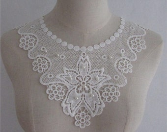 Può includere: Colletto in pizzo bianco con un delicato motivo floreale e decorazioni di perle. Il colletto è perfetto per aggiungere un tocco di eleganza a qualsiasi outfit.