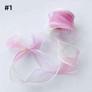May include: A roll of sheer ribbon in shades of pink and white, with a delicate white trim. A bow made from the same ribbon is also visible. The ribbon is labeled with the number "#1".