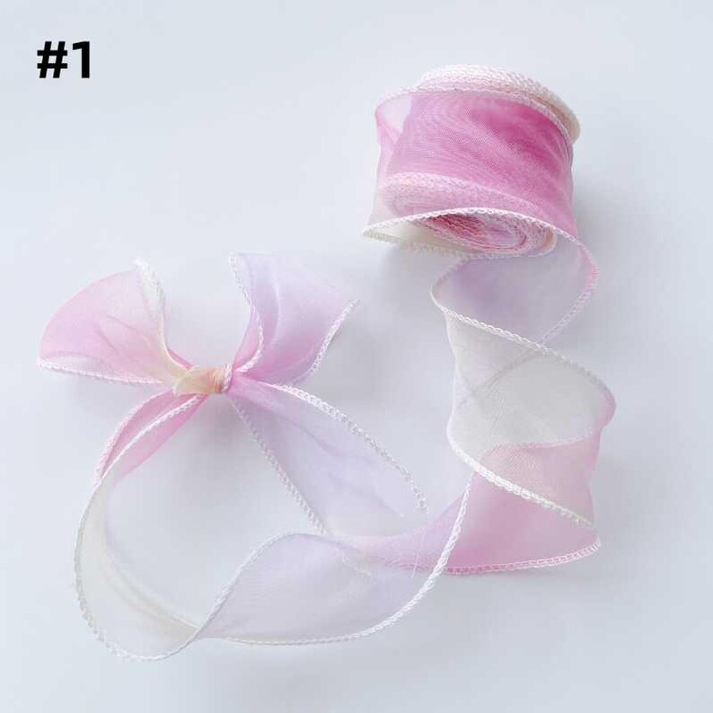 May include: A roll of sheer ribbon in shades of pink and white, with a delicate white trim. A bow made from the same ribbon is also visible. The ribbon is labeled with the number "#1".