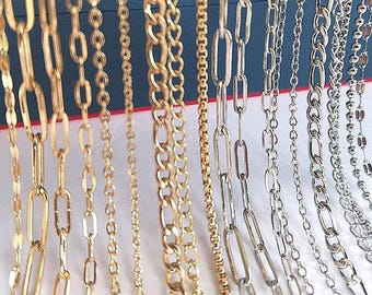 Könnte beinhalten: Eine Sammlung gold- und silberfarbener Kettenhalsketten in verschiedenen Stilen. Die Ketten weisen unterschiedliche Gliederdesigns auf, darunter ovale, Curb- und Perlenstile. Die Halsketten werden vor blauem Hintergrund präsentiert.
