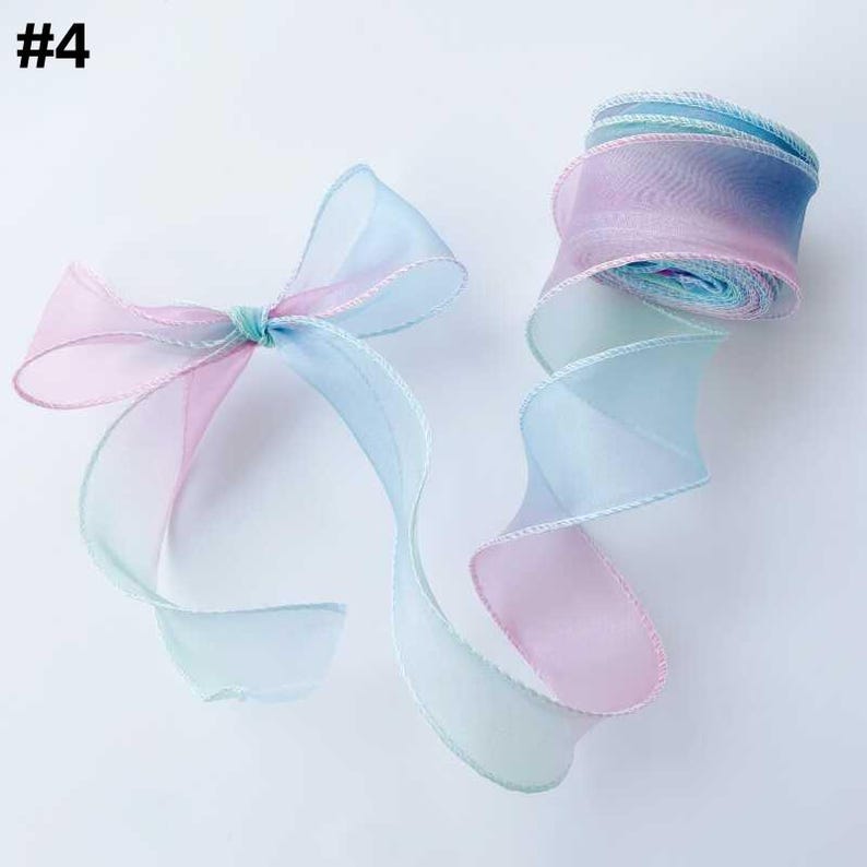 May include: A pastel-colored ribbon, featuring shades of pink, blue, and green, is displayed. The ribbon is arranged in a bow and a rolled-up spool. The edges of the ribbon are trimmed with a white thread. The number "#4" is in the top left corner.