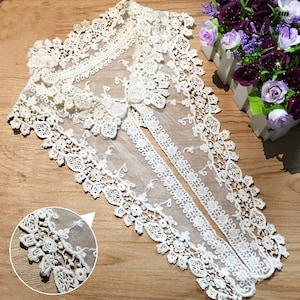 Puede incluir: Collar de encaje blanco con un delicado diseño floral. El collar está hecho de una tela transparente y tiene un borde festoneado.