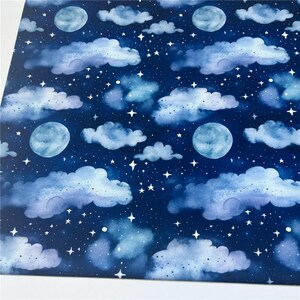 May include: A seamless pattern featuring watercolor clouds and moons on a dark blue background. The clouds are light blue and white, and the moons are a light blue color. The pattern is perfect for fabric, wallpaper, or wrapping paper.