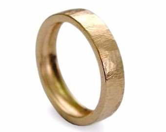 May include: A simple, brushed gold wedding band. The band is smooth and has a slightly hammered texture.