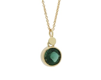 May include: A gold chain necklace with a green gemstone pendant. The pendant is round and has a bezel setting.