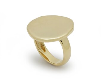 Puede incluir: Un anillo de oro con una parte superior grande, plana y ovalada.