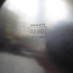 May include: Close-up of a stainless steel surface with the words "Stainless Old Hall England" engraved on it.