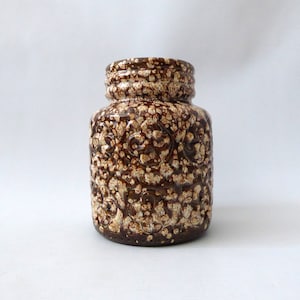 May include: A brown and white ceramic vase with a speckled glaze and embossed floral pattern.