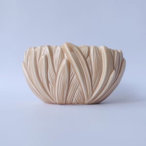 May include: A light brown ceramic bowl with a decorative design of overlapping leaves.