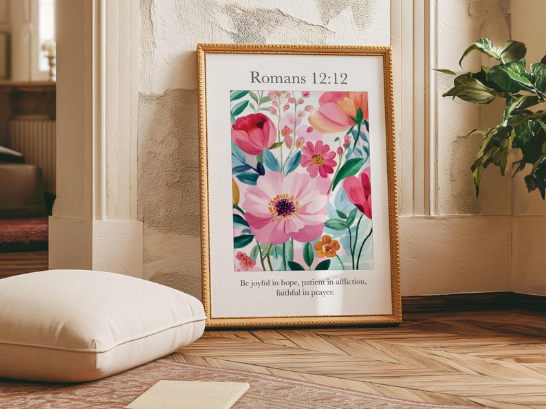 May include: A framed print with a floral design in shades of pink, red, and green. The print features the text "Romans 12:12" and the quote "Be joyful in hope, patient in affliction, faithful in prayer."