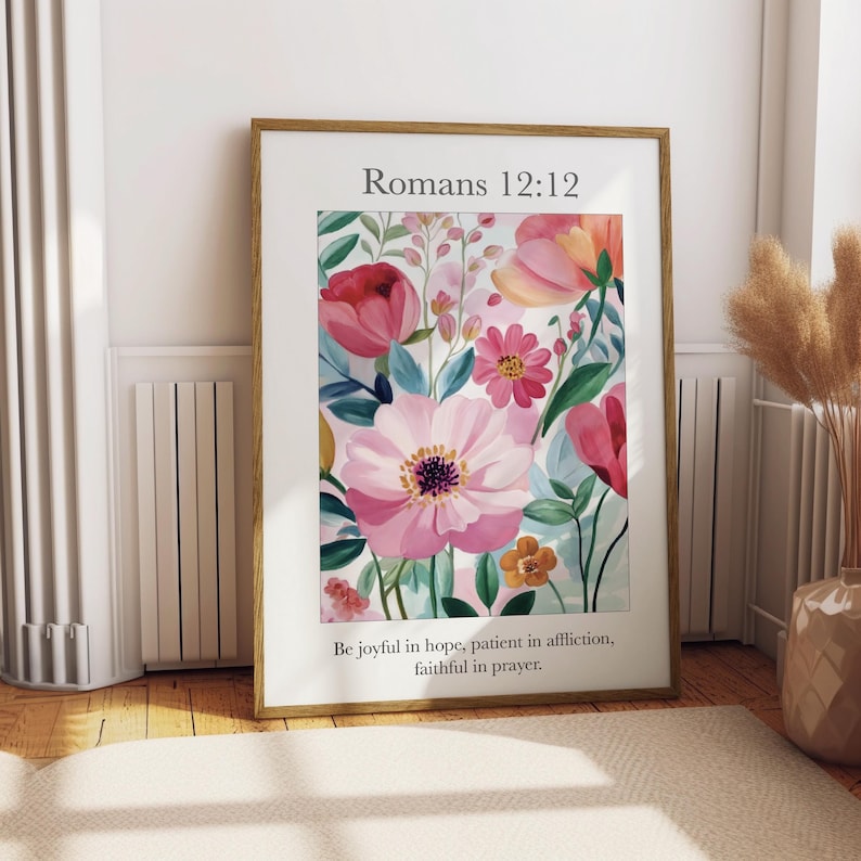 May include: A framed print with a floral design featuring pink, red, and yellow flowers. The print includes the text "Romans 12:12" and the quote "Be joyful in hope, patient in affliction, faithful in prayer."
