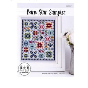Op de afbeelding: Een ingelijst kruissteekpatroon getiteld "Barn Star Sampler". Het ontwerp toont een raster van kleurrijke sterren en geometrische patronen in tinten rood, blauw, geel en groen. Het patroon is 137w x 161h. Het kunstwerk is van Cora's Quilts by Shirley Corana.