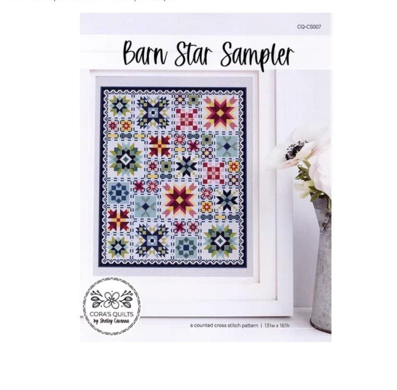 Op de afbeelding: Een ingelijst kruissteekpatroon getiteld "Barn Star Sampler". Het ontwerp toont een raster van kleurrijke sterren en geometrische patronen in tinten rood, blauw, geel en groen. Het patroon is 137w x 161h. Het kunstwerk is van Cora's Quilts by Shirley Corana.