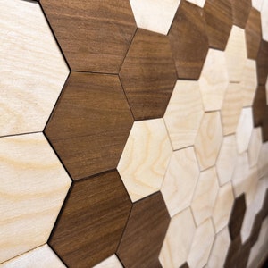 May include: A wall covered in a geometric pattern of hexagonal tiles. The tiles are made of wood and are arranged in a staggered pattern. The tiles are in two colors: light brown and dark brown.