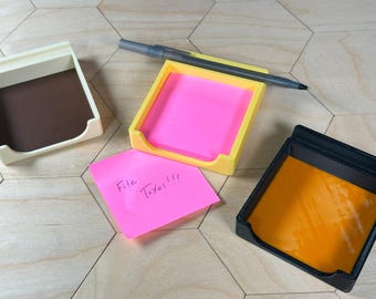 May include: Three desk organizers, one yellow, one white, and one black, with a pink sticky note that says "File Taxes!!!" in black ink.