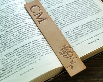 May include: A brown leather bookmark with the initials "CM" embossed in gold. The bookmark features a decorative rose design.