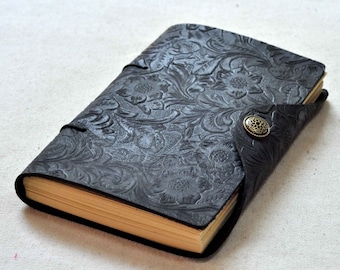 May include: A black leather journal with a floral embossed design and a brass button closure.