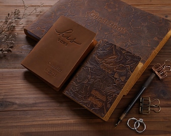 May include: A collection of brown leather wedding stationery, including a guest book and vow books. The guest book is embossed with floral patterns and the words "Guest Book." The vow books are embossed with "his vows" and "her vows" and names and dates.