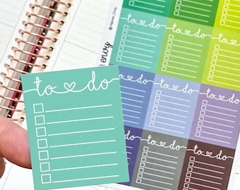 Peut inclure: Un autocollant de liste de tâches turquoise avec un cœur au-dessus des mots et une liste de contrôle de cases. L'autocollant est tenu au-dessus d'un agenda avec d'autres autocollants de liste de tâches colorés.