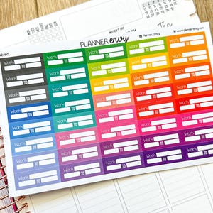 May include: A sheet of colorful planner stickers with the text "Work TO" in white on a variety of colored backgrounds. The stickers are arranged on a white sheet, with a calendar and the text "PLANNER envy" visible.