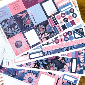 Könnte beinhalten: Ein Set Planer-Aufkleber mit floralen Designs in Rosa-, Blau- und Lilatönen. Die Aufkleber enthalten Kästchen zum Schreiben, Checklisten und verschiedene Symbole wie ein Haus, ein Auto, einen Einkaufswagen und ein Herz.
