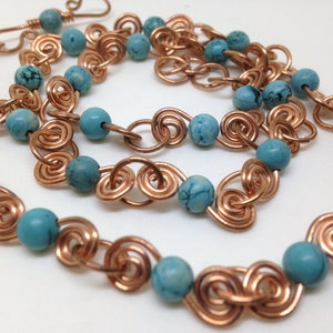 May include: A copper chain necklace with turquoise beads. The chain is made of wire that is twisted into a spiral shape.