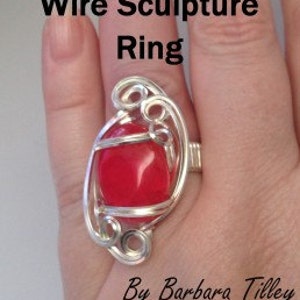 May include: A silver wire ring with a red gemstone set in the center. The wire is twisted and curled to create a decorative design.