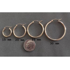 May include: Four gold hoop earrings of different sizes, measuring 15 mm, 20 mm, 25 mm, and 30 mm. A US dime is included for size comparison.