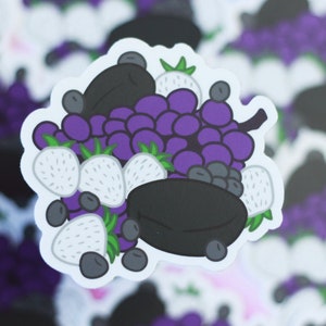May include: A sticker featuring a cartoon illustration of a pile of fruit, including blackberries, grapes, and strawberries. The fruit is arranged in a bowl-like shape, with a black background.