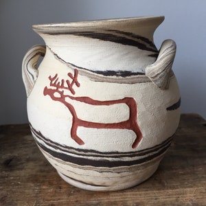 May include: A white ceramic vase with brown and black stripes. The vase has two handles and a red reindeer design.